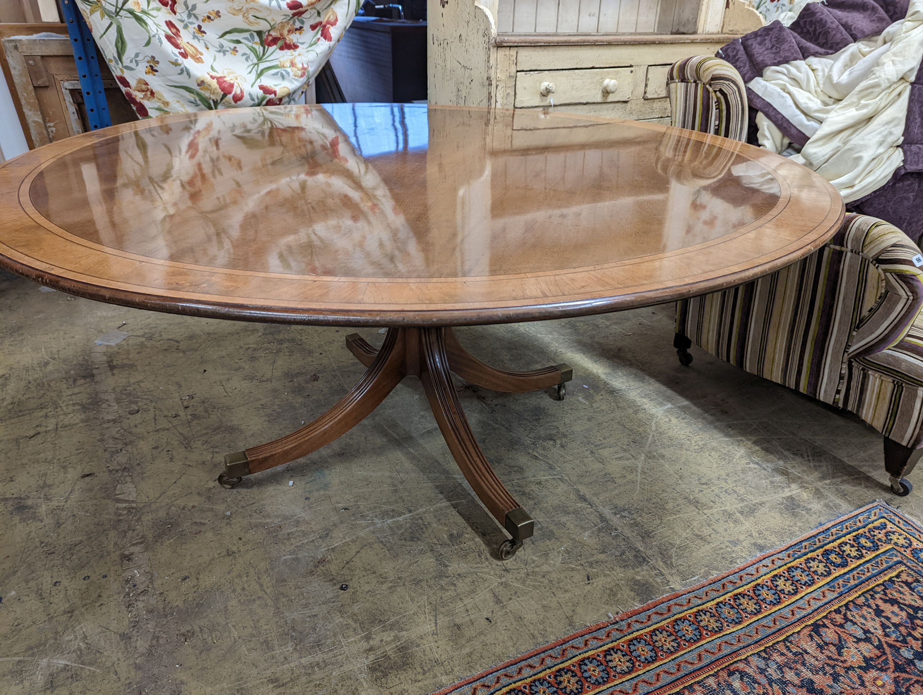 Attributed to William Tillman, a reproduction George III style banded mahogany circular pedestal tilt top dining table, diameter 160cm, height 72cm